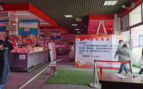 　　猪肉大厅进门处立着“温馨提示”牌，提醒顾客戴好口罩，保持距离，移动支付。摄影/新京报记者 陈琳